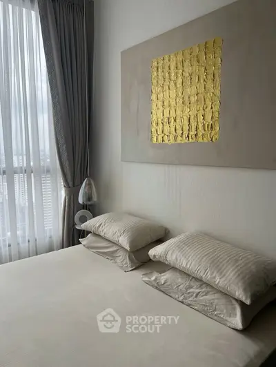 Elegant bedroom with modern decor and large window offering natural light.