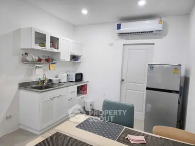 Modern kitchen with sleek white cabinets and stainless steel appliances in a cozy apartment.