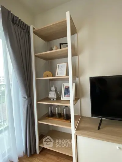 Modern living room with stylish shelving and TV unit, featuring elegant decor and natural light.