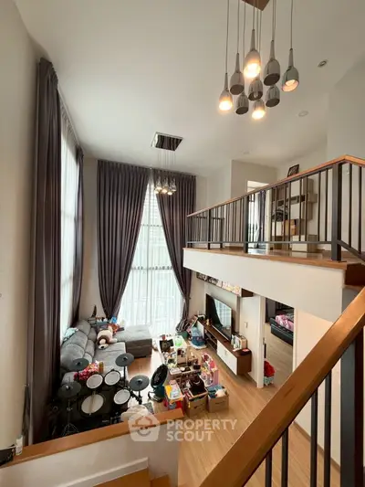 Spacious living room with high ceilings and modern decor, featuring a cozy seating area and stylish lighting.