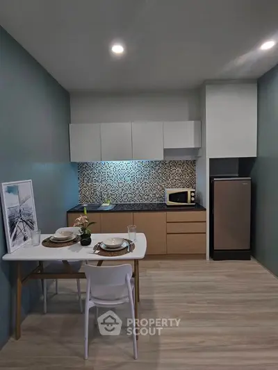 Modern kitchen with sleek cabinetry and dining area in stylish apartment.