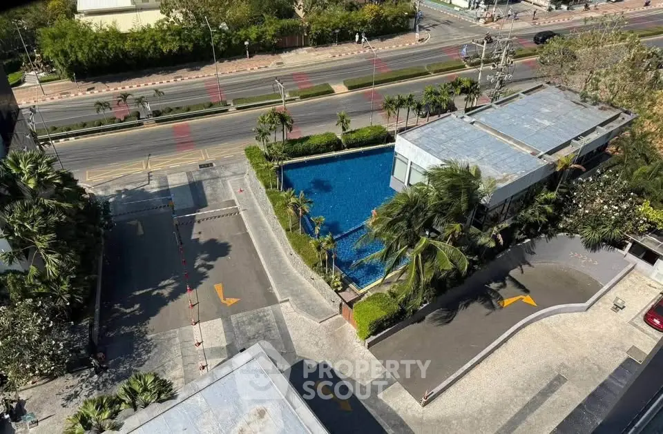 Aerial view of modern building with pool and landscaped surroundings.