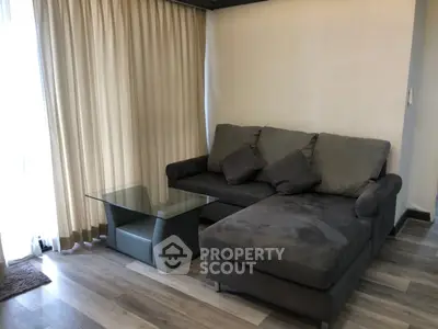 Cozy living room with modern gray sectional sofa and glass coffee table, perfect for relaxation.
