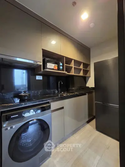 Modern kitchen with sleek cabinetry, washing machine, and stainless steel appliances