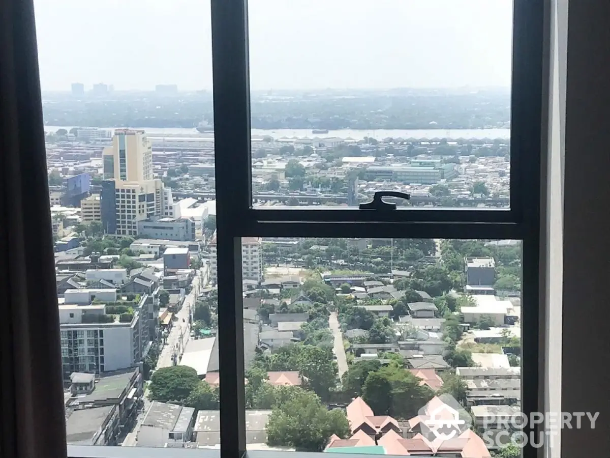 Stunning high-rise cityscape view from apartment window showcasing urban landscape and river.