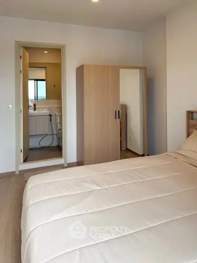 Modern bedroom with ensuite bathroom and wooden wardrobe, featuring a cozy bed and neutral decor.