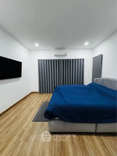 Spacious modern bedroom with wooden flooring and sleek decor