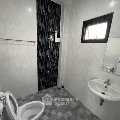 Modern bathroom with sleek black tile accent wall and compact fixtures.