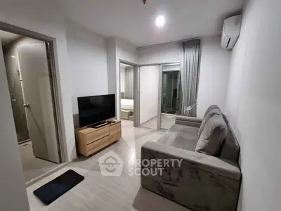 Modern living room with cozy sofa, flat-screen TV, and sleek wooden flooring in a stylish apartment.