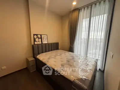 Modern bedroom with large window and stylish decor in a high-rise apartment.