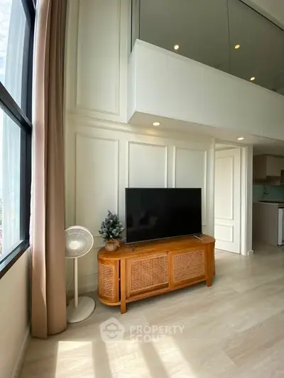 Modern living room with high ceiling and large window, featuring a stylish TV stand and elegant decor.