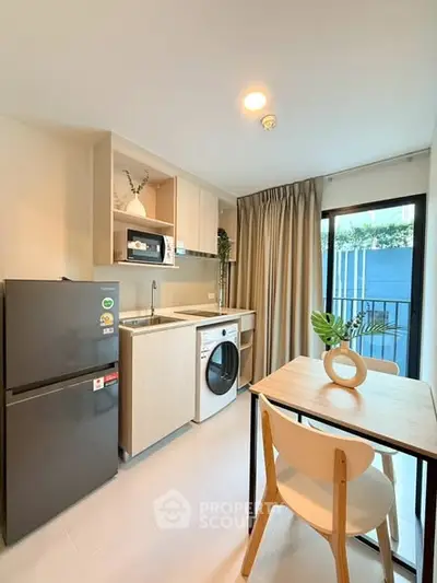 Modern kitchen with washing machine and dining area in bright apartment