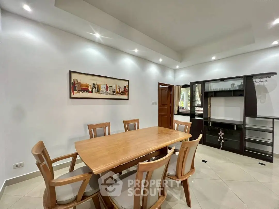 Spacious dining area with elegant wooden table and chairs, modern lighting, and stylish decor.