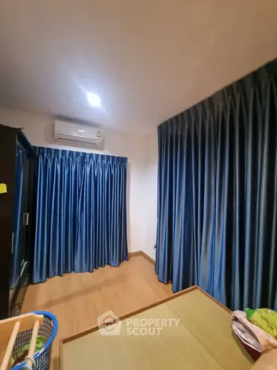 Cozy bedroom with blue curtains and air conditioning, perfect for relaxation.