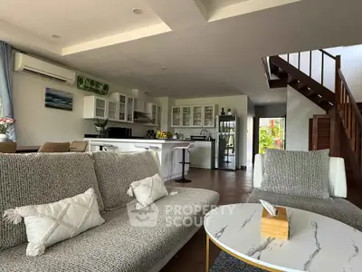 Spacious open-plan living room with modern kitchen and stylish staircase in a contemporary home.