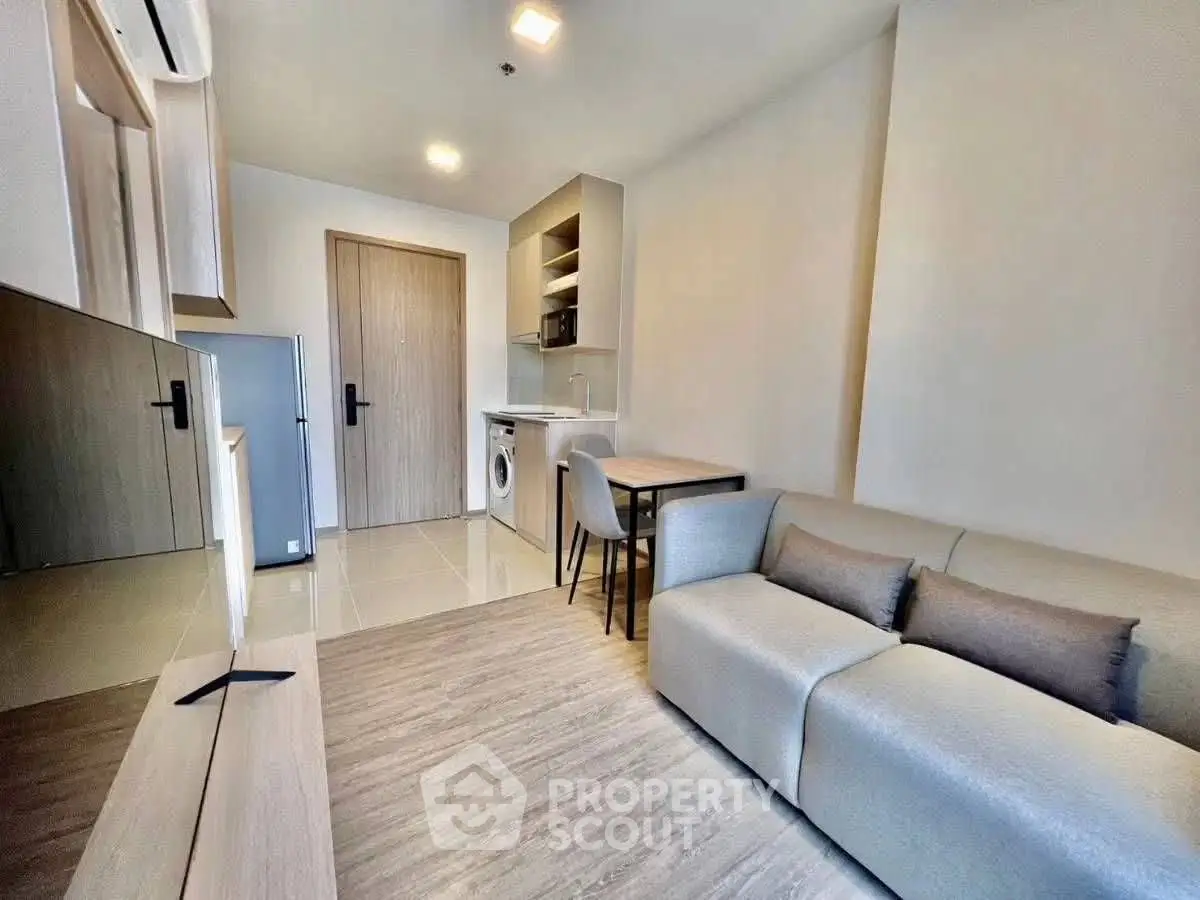 Modern living room with compact kitchen and cozy seating area in a stylish apartment.