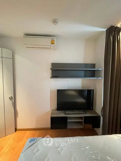 Modern bedroom with air conditioning and TV setup, featuring sleek shelves and cozy ambiance.