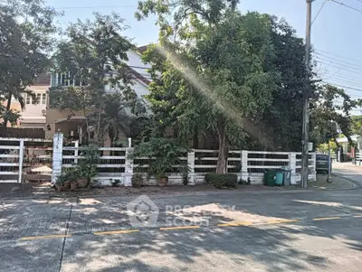 Charming suburban house with lush greenery and white picket fence on a sunny day.
