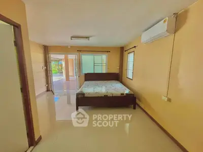 Spacious bedroom with modern air conditioning and large windows for natural light.