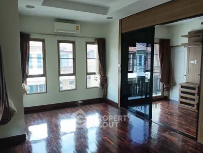 Spacious bedroom with wooden flooring and large windows in modern apartment
