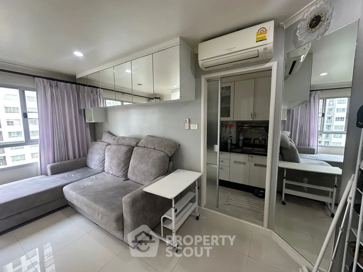 Modern living room with gray sofa and mirrored accents in a high-rise apartment.