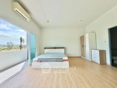 Spacious bedroom with balcony access and modern furnishings in a bright, airy apartment.