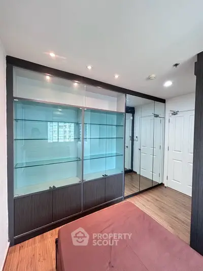 Modern bedroom with built-in glass shelving and mirrored wardrobe in a stylish apartment.