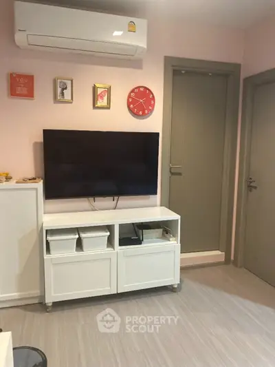 Cozy living room with modern decor, wall-mounted TV, and air conditioning unit.