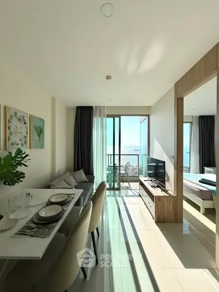 Modern open-plan living room with dining area and balcony offering stunning sea view.