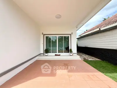 Charming covered patio with sliding glass doors and potted plants, perfect for outdoor relaxation.