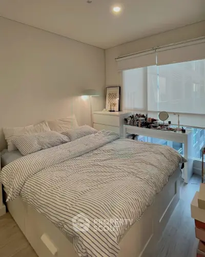 Cozy bedroom with striped bedding and natural light, featuring a stylish makeup vanity and modern decor.