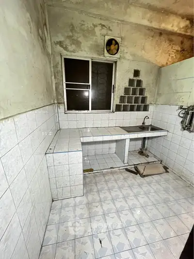Spacious kitchen with tiled walls and floor, featuring a large window for natural light.
