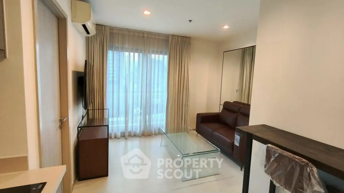 Modern living room with glass coffee table and brown leather sofa in a cozy apartment.