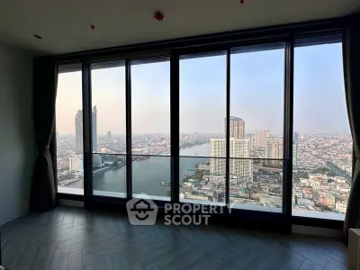 Spacious high-rise corner unit with floor-to-ceiling windows offering panoramic city and river views, bathed in natural light, ideal for luxurious urban living.
