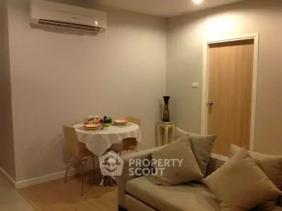 Cozy living room with modern decor and dining area, featuring a comfortable sofa and air conditioning.