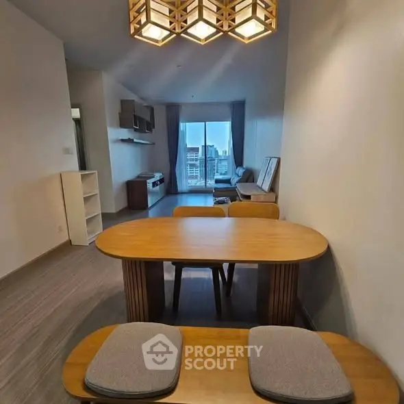 Modern living room with dining area and city view, featuring stylish lighting and contemporary furniture.