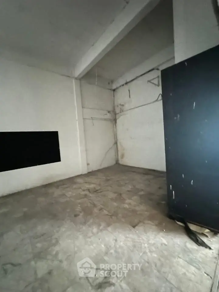 Spacious industrial-style room with high ceilings and concrete flooring, ideal for creative workspace or storage.