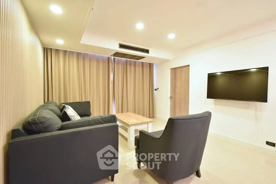 Modern living room with cozy seating and wall-mounted TV in a stylish apartment.