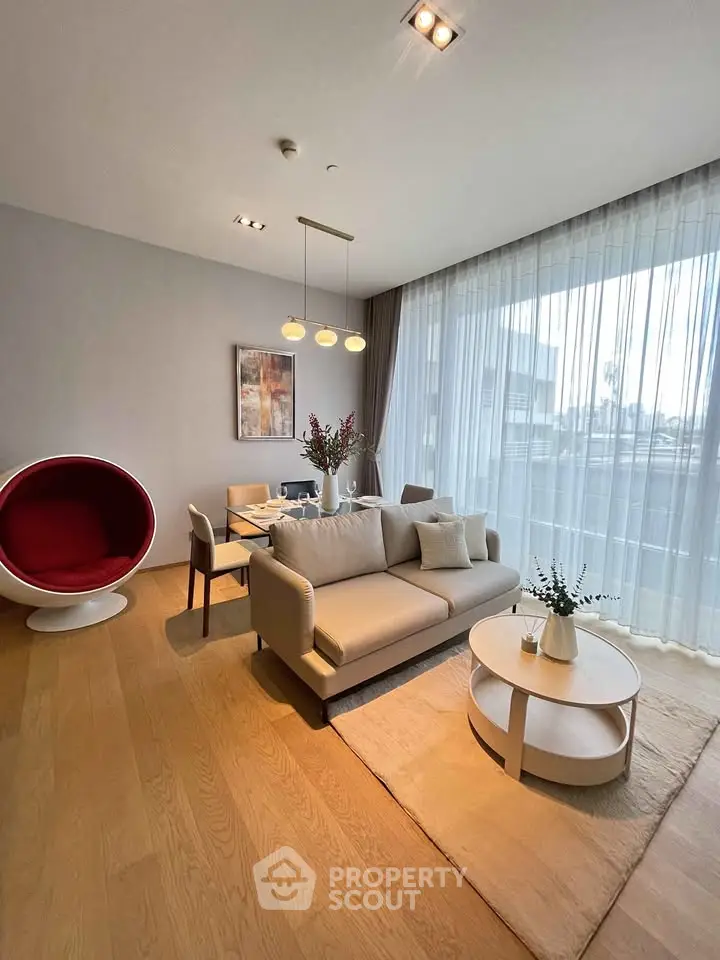 Modern living room with stylish furniture and large window offering natural light.