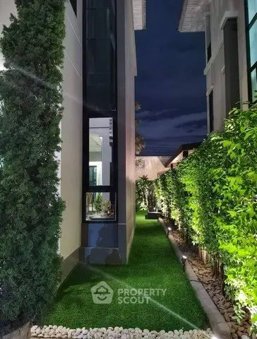 Luxurious modern garden pathway with lush greenery and ambient lighting at night.