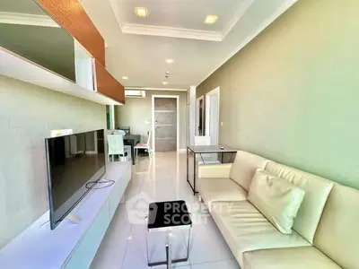 Modern living room with sleek design and neutral tones, featuring a comfortable sofa and large TV.