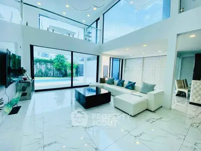Luxurious modern living room with high ceilings and large windows overlooking a pool.