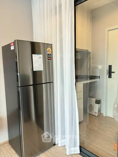 Modern kitchen with sleek stainless steel fridge and glass partition, perfect for contemporary living.