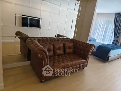 Luxurious open-plan living room with elegant brown leather sofa and mirrored wall accent
