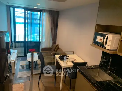 Modern compact living room with kitchenette and balcony view, featuring sleek furniture and contemporary design.