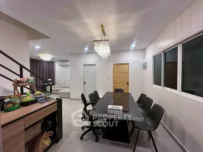 Modern dining area with sleek black table and elegant chandelier in a stylish open-plan living space.