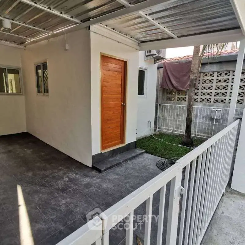 Charming outdoor area with covered patio and wooden door, perfect for relaxation.