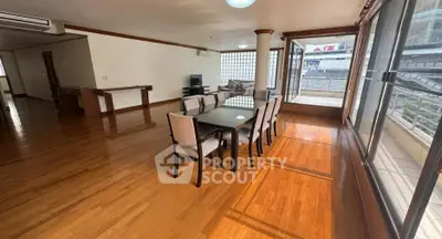 Spacious dining area with large windows and wooden flooring in modern apartment.