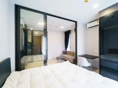 Modern studio apartment with glass partition, cozy living area, and sleek furnishings.