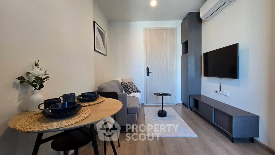 Modern living room with cozy sofa, wall-mounted TV, and stylish dining area.